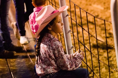 Girl in Cowgirl Hat Looking Through Fence 